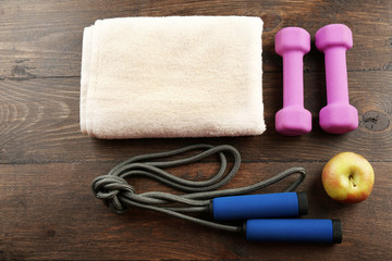 Obraz na płótnie Canvas Sport equipment, towel and apple on wooden background