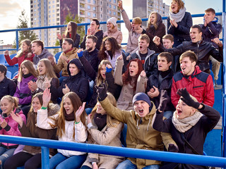 Sport fans clapping and singing on tribunes.