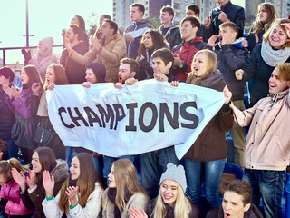 Sport fans holding champion banner on tribunes.