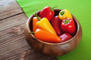Colorful bell pepper in a wooden bowl on the table