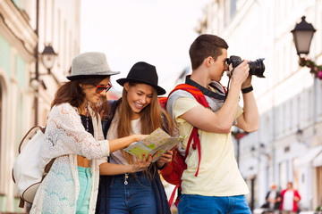 Three friends together with city map and camera