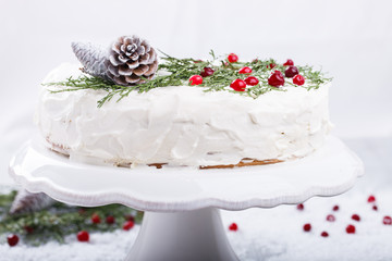 Cake with white cream,garnished with sprigs of spruce ,pine cones,cranberries.
