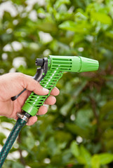man hand with hose watering garden