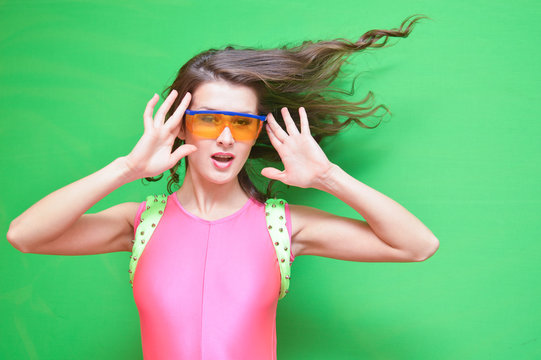 Lady with flipping hair wearing safety glasses and pink jumpsuit