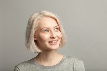 Fototapeta premium smiling blonde woman looking right on gray background