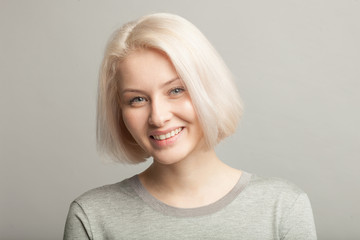 close up portrait of blonde smiling woman on gray background