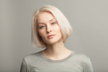 close up portrait of young beautiful blonde woman on gray background