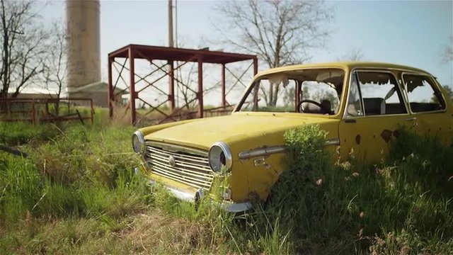 An old broken down car sits abandoned in a field