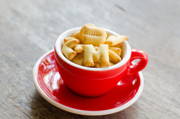 alphabet cookies in red cup on wooden background