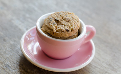 cookies in pink cup on wooden table