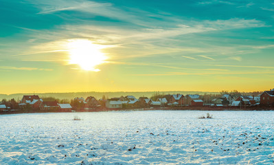 Obraz premium Winter landscape: field, houses, sunset