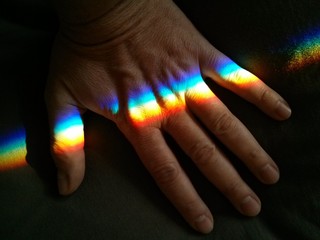 Male hand palm fingers with rainbow crossing on a dark background closeup