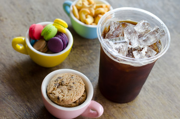 black ice coffee and dessert in cup on wooden background