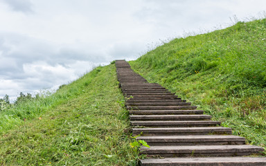 Long wood stairs to top of grass-covered earth-deposit. Belozersk, Vologodsky region, Russia. 
