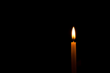 One frame light candle burning brightly in the black background