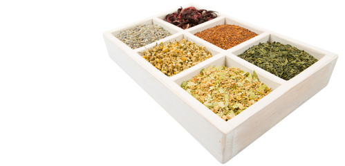 Dried herbal tea leaves, lavender, rooibos, chamomile, linden flower, hibiscus, Japanese green tea in white wooden box over white background