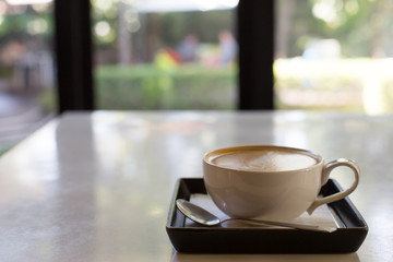Hot art Latte Coffee in a cup and laptop on wooden table.