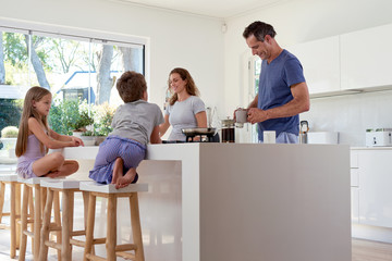family in kitchen, parents preparing breakfast - 97480898