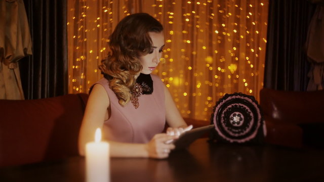 elegant girl in a restaurant is overwritten with a friend on the tablet