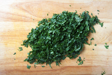 Finely chopped fresh parsley on a light wooden table or cutting