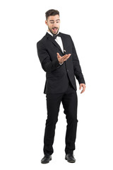 Playful excited young groom tossing wedding ring. Full body length portrait isolated over white studio background. 