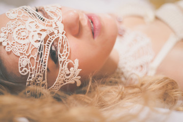 Beautiful blonde lady with white lace mask over her eyes 