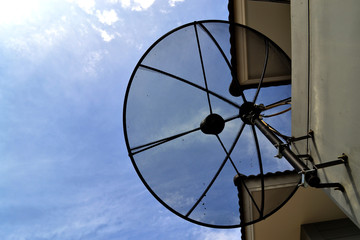 Satellite dish on wall with blue sky