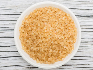 Brown sugar in white bowl over wooden background