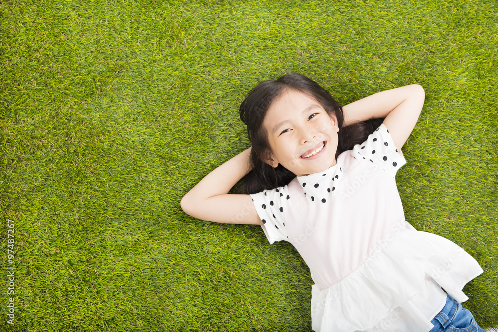 Wall mural happy little girl resting on the grass