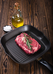 Raw marbled meat steak Ribeye on grill pan on dark wooden background