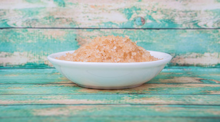 Brown sugar in white bowl over wooden background