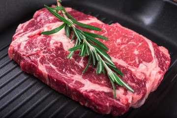 Raw marbled meat steak Ribeye on grill pan on dark wooden background