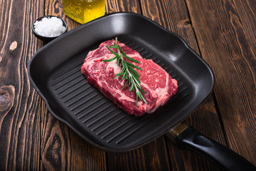Raw marbled meat steak Ribeye on grill pan on dark wooden background