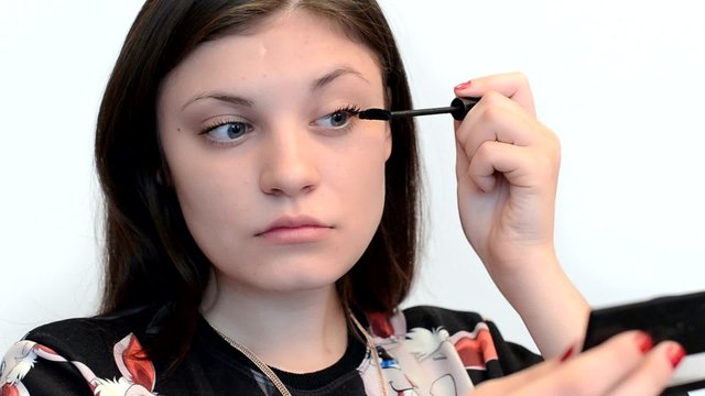 Девушка делает макияж , красит ресницы тушью. Видео на белом фоне.