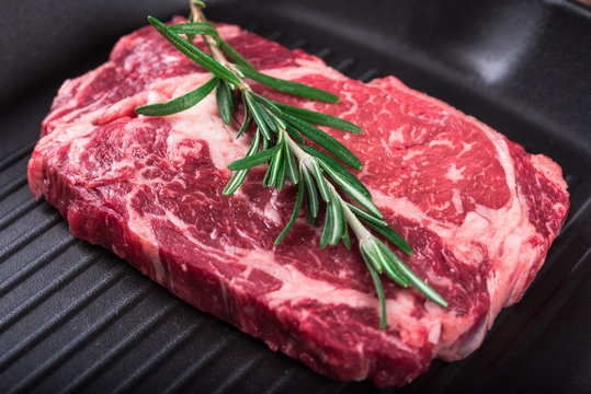 Raw marbled meat steak Ribeye on grill pan on dark wooden background