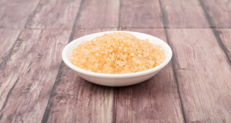 Brown sugar in white bowl over wooden background