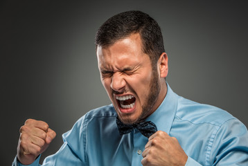 Portrait angry upset young man in blue shirt, butterfly tie 