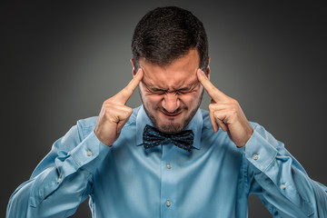 Portrait angry upset young man in blue shirt, butterfly tie 