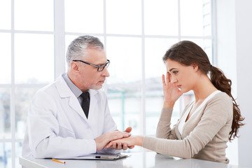 Aged doctor with patient in hospital office