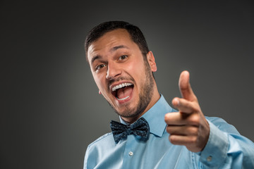 Smiling man is gesturing with hand, pointing finger at camera