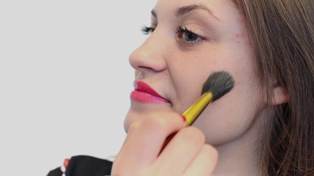 Молодая женщина делает макияж., с помощью пудры