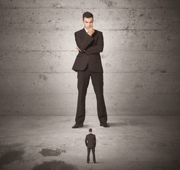 Huge business guy looking at small coworker