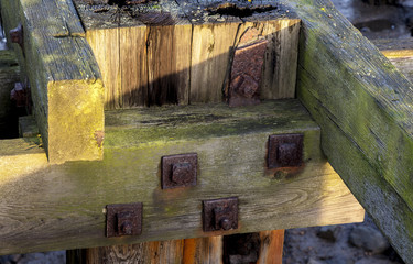 Details of wooden joints of old wooden jetty, showing rusty knuts and bolts.
