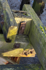 Details of wooden joints of old wooden jetty, showing rusty knuts and bolts.