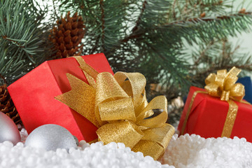 Red boxes with gold ribbon in snow  under pine tree