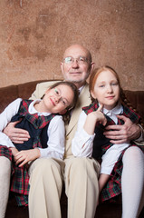Дед и две внучки обнимаются и улыбаются в костюмах