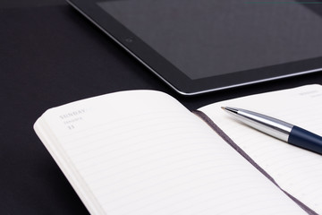 Open daily planner with luxury ball pen and tablet computer