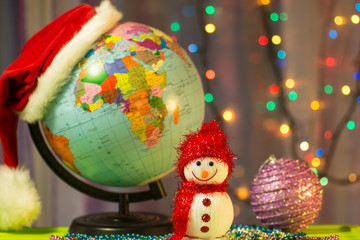 Merry Christmas Snowman on the background of the globe in a cap of Santa Claus