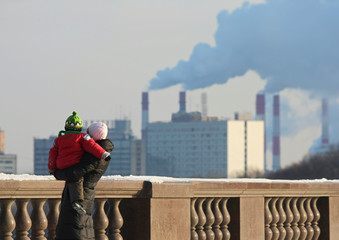 Woman with the child against pipes with a smoke