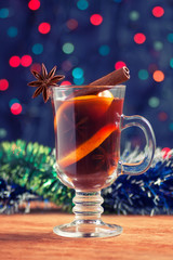 mulled wine with tinsel on a wooden table on bokeh background